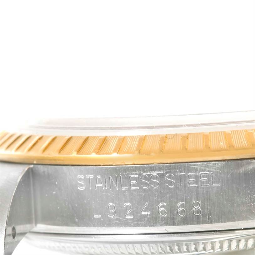 The image shows a close-up of the side profile of a Rolex Date 15223 Men's Steel and Gold (two tone) Champagne Dial 15223 Men's Steel and Gold (two tone) Champagne Dial model watch, featuring its bezel and part of the case with serial number.