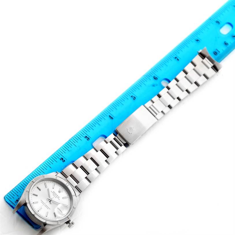 The Rolex Date 15210 Men's Stainless Steel Silver Dial 15210 Men's Stainless Steel Silver Dial model watch is shown from a top-down angle, detailing the face, bracelet, and clasp, aligned with a blue ruler.