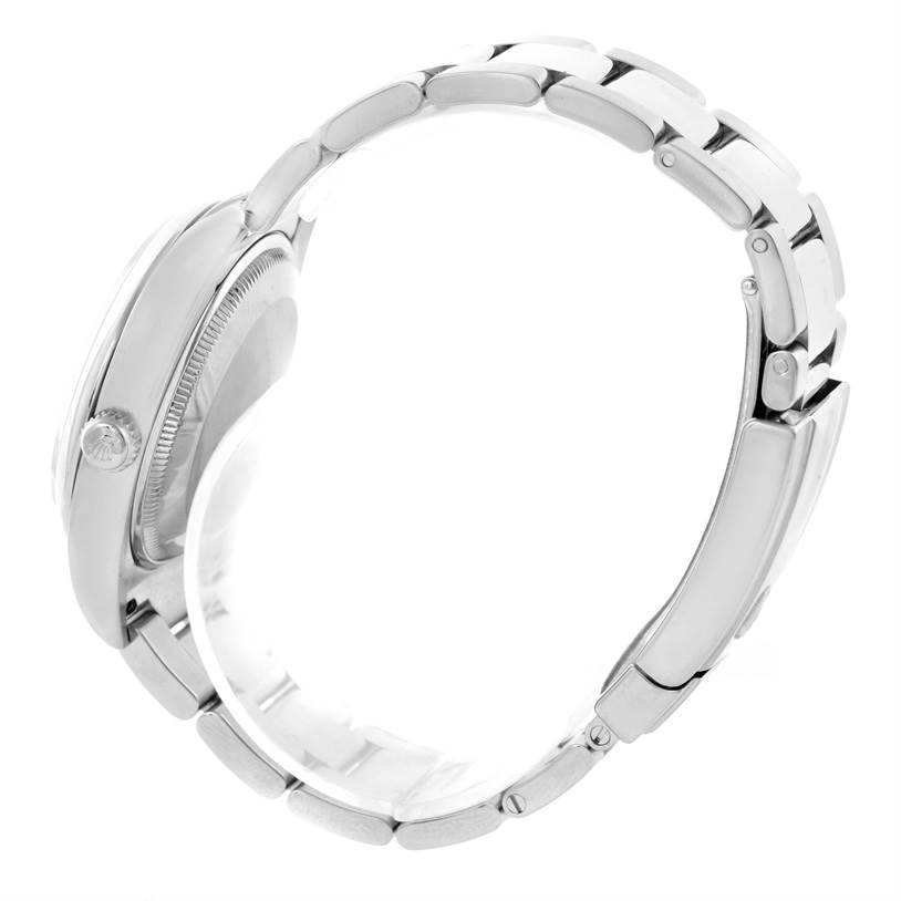 The Rolex Date 115200SRO Men's Stainless Steel White Dial 115200SRO Men's Stainless Steel White Dial watch is shown from the side angle, displaying the case, crown, bracelet, and clasp.