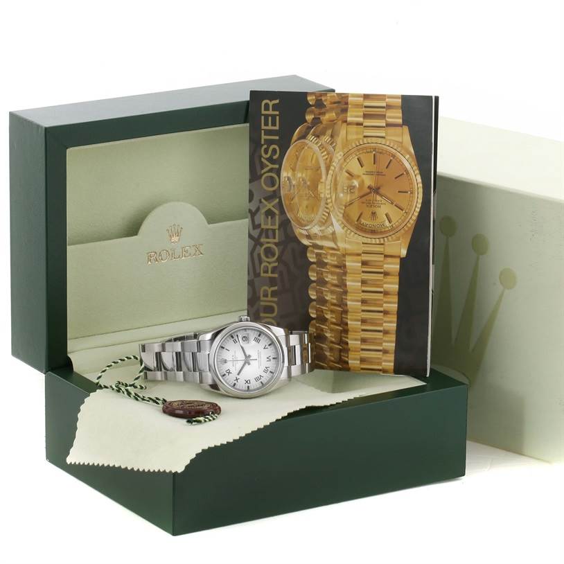 The image shows a Rolex Date 115200SRO Men's Stainless Steel White Dial 115200SRO Men's Stainless Steel White Dial watch in its open box, accompanied by a booklet, tag, and cleaning cloth.