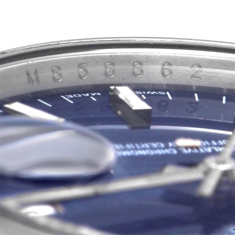 This close-up image of the Rolex Date 115200 Men's Stainless Steel Blue Dial 115200 Men's Stainless Steel Blue Dial model shows part of the dial, hands, and serial number engraving on the inner bezel.