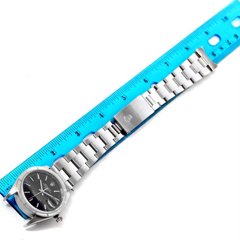 The image shows a flat view of a Rolex Date 15210 Men's Stainless Steel Black Dial 15210 Men's Stainless Steel Black Dial model watch with a full stainless steel bracelet and a blue measuring ruler.