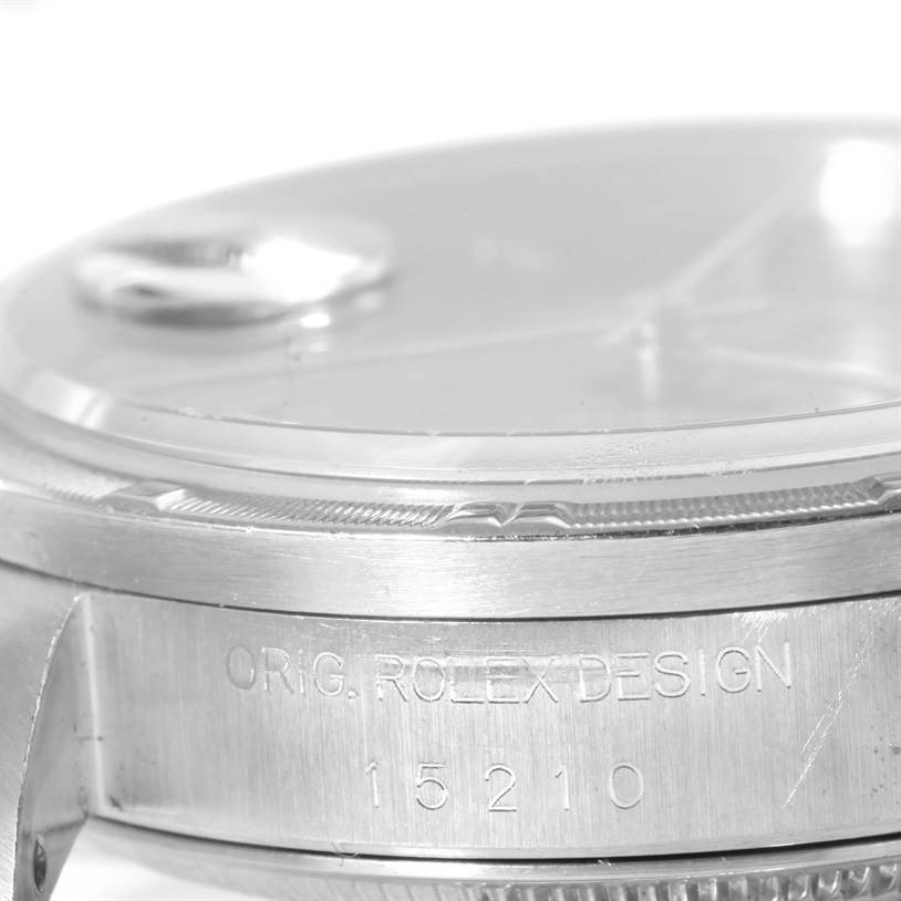 This image shows a close-up side view of a Rolex Date 15210 Men's Stainless Steel Blue Dial 15210 Men's Stainless Steel Blue Dial model watch, highlighting the engraved case design and bezel.