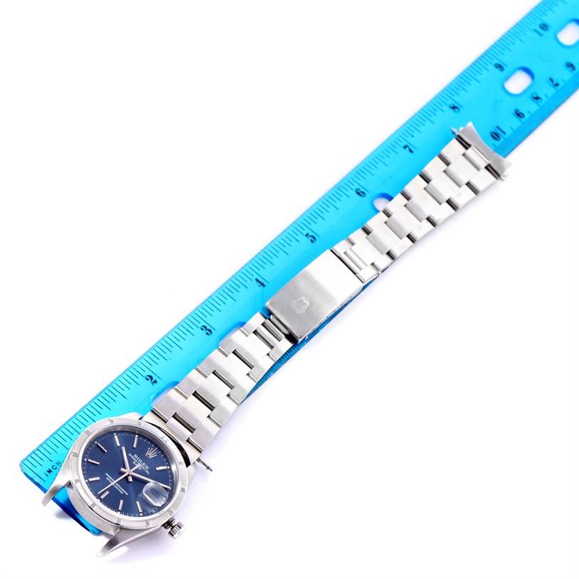 The Rolex Date 15210 Men's Stainless Steel Blue Dial 15210 Men's Stainless Steel Blue Dial model watch is shown horizontally with the band extended alongside a ruler for measurement.