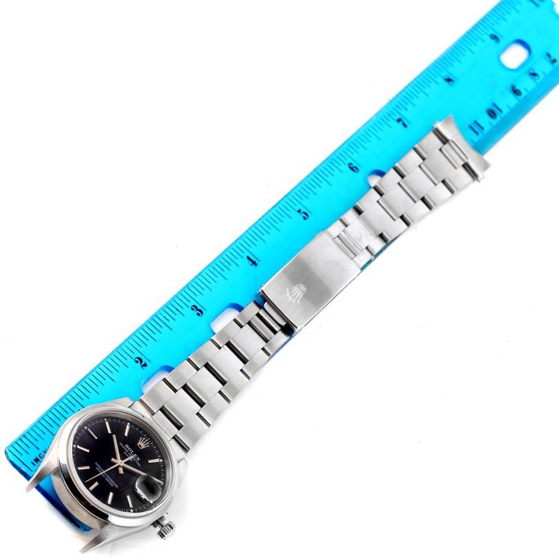 The Rolex Date 15200 Men's Stainless Steel Black Dial 15200 Men's Stainless Steel Black Dial watch is shown from an overhead angle, displaying the face, bracelet, and clasp with a ruler for scale.