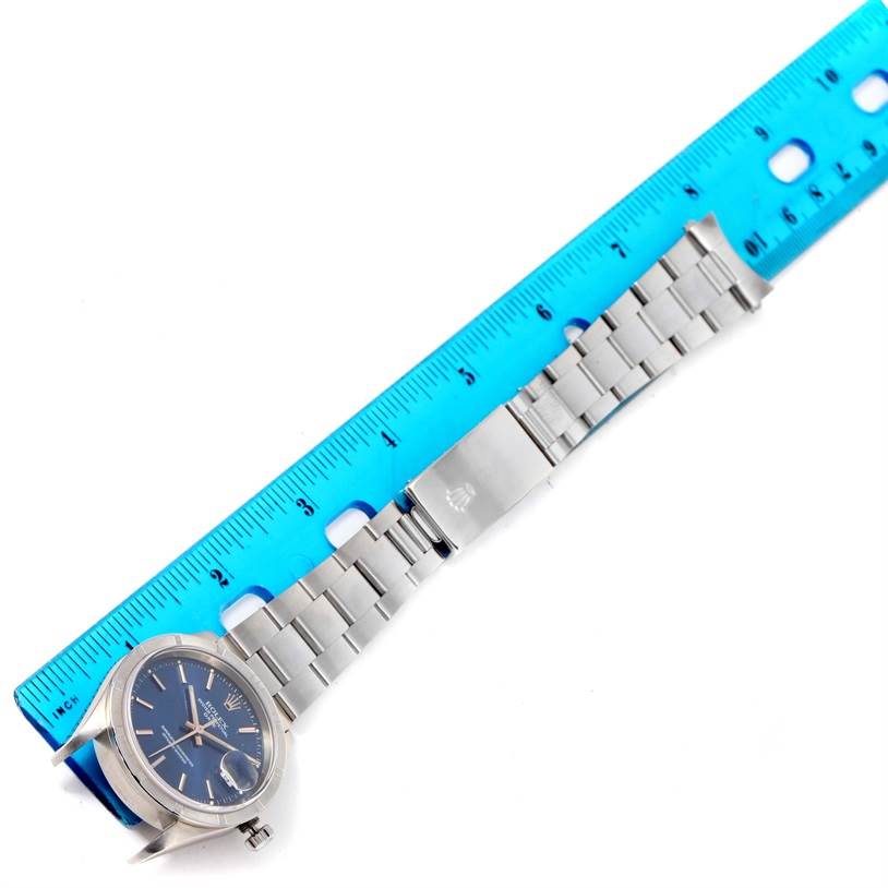 The image shows a Rolex Date 15210 Men's Stainless Steel Blue Dial 15210 Men's Stainless Steel Blue Dial model watch from an angled top-down view, alongside a blue ruler for scale.