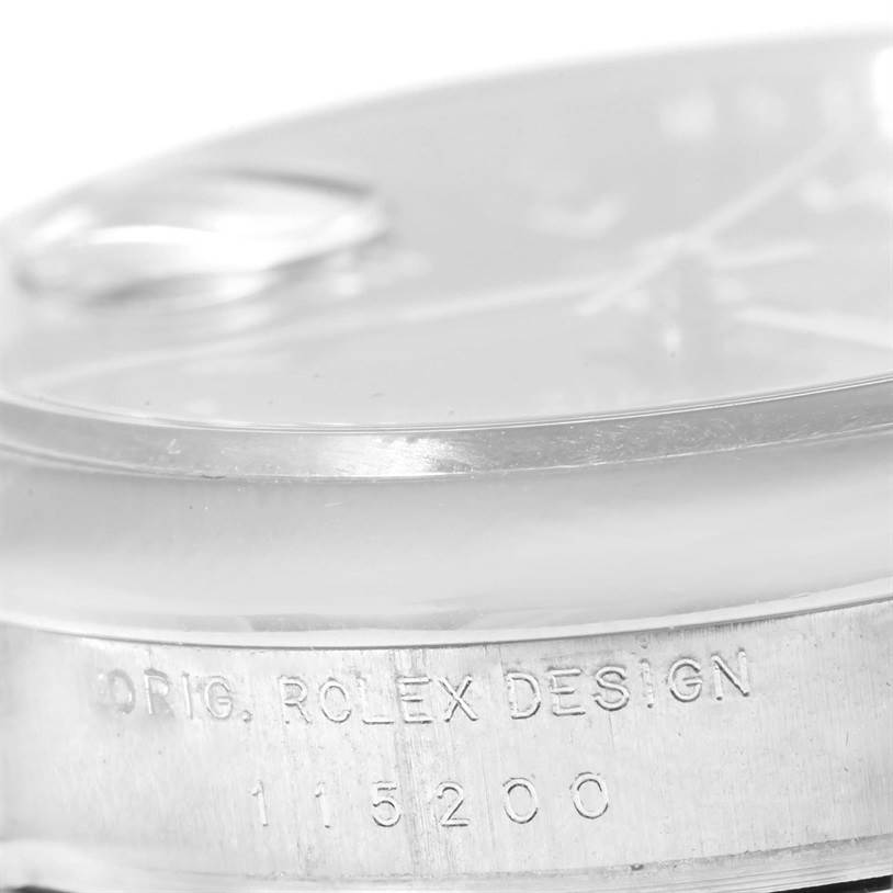 The image shows a close-up of the side of the Rolex Date 115200 Men's Stainless Steel Black Dial 115200 Men's Stainless Steel Black Dial model watch with an engraving of the design number.