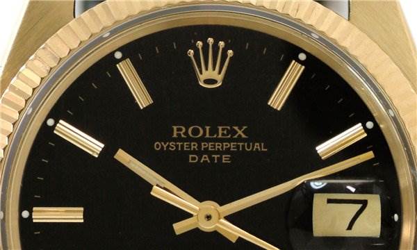 The image shows the face of a Rolex Oyster Perpetual Date watch at a close-up angle, highlighting the dial, hands, and date window.