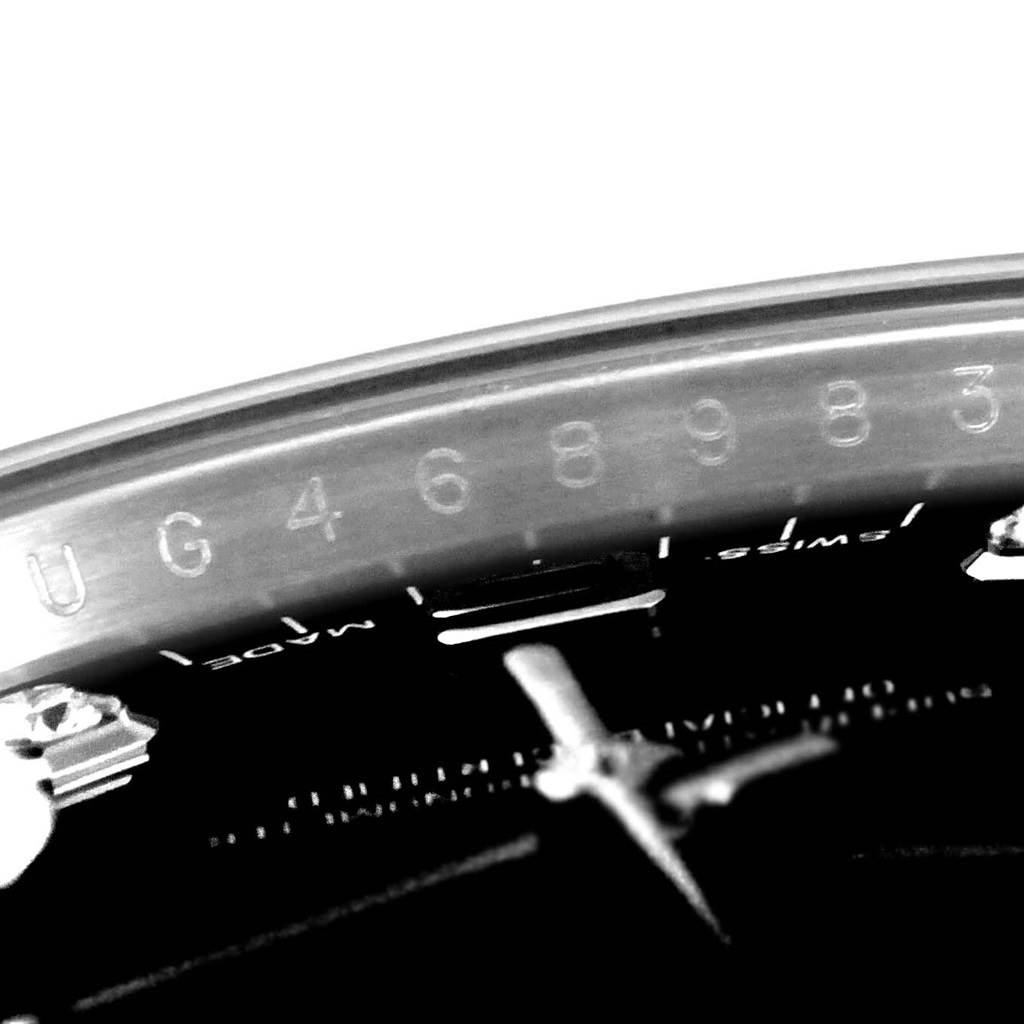 This close-up image of the Rolex Date 115234 Men's Stainless Steel Black Dial 115234 Men's Stainless Steel Black Dial model watch shows part of the bezel with serial numbers and a portion of the dial.