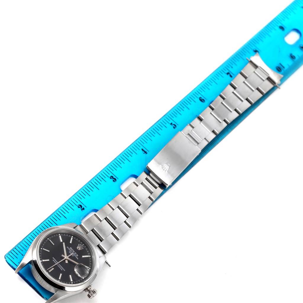 The image shows a Rolex Date 15200 Men's Stainless Steel Black Dial 15200 Men's Stainless Steel Black Dial watch laid flat with its metal strap alongside a blue ruler for scale.