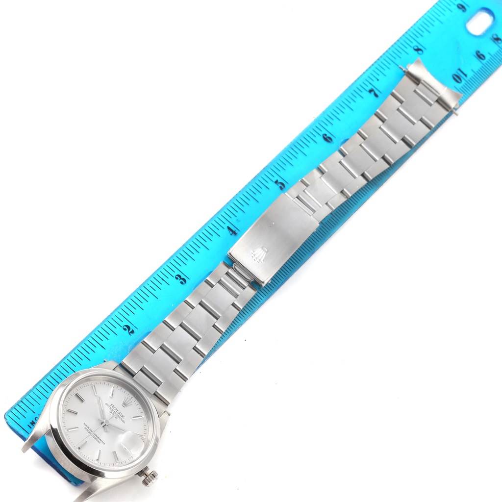 The Rolex Date 15200 Men's Stainless Steel Silver Dial 15200 Men's Stainless Steel Silver Dial model watch is displayed flat, showing the face, case, bracelet, and clasp next to a blue ruler.