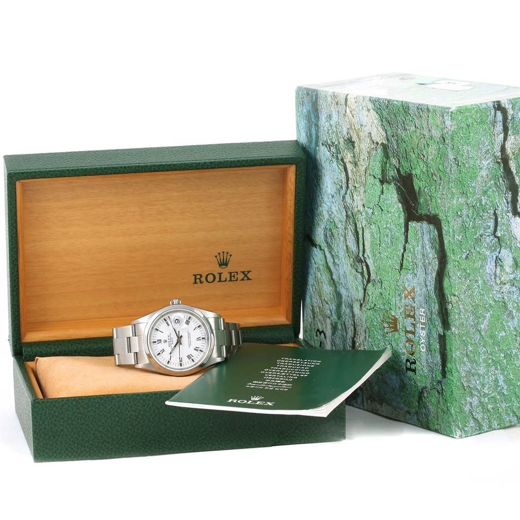 The image shows a Rolex Date 15200 Men's Stainless Steel White Dial 15200 Men's Stainless Steel White Dial model watch along with its green box, wooden interior, and accompanying booklet.