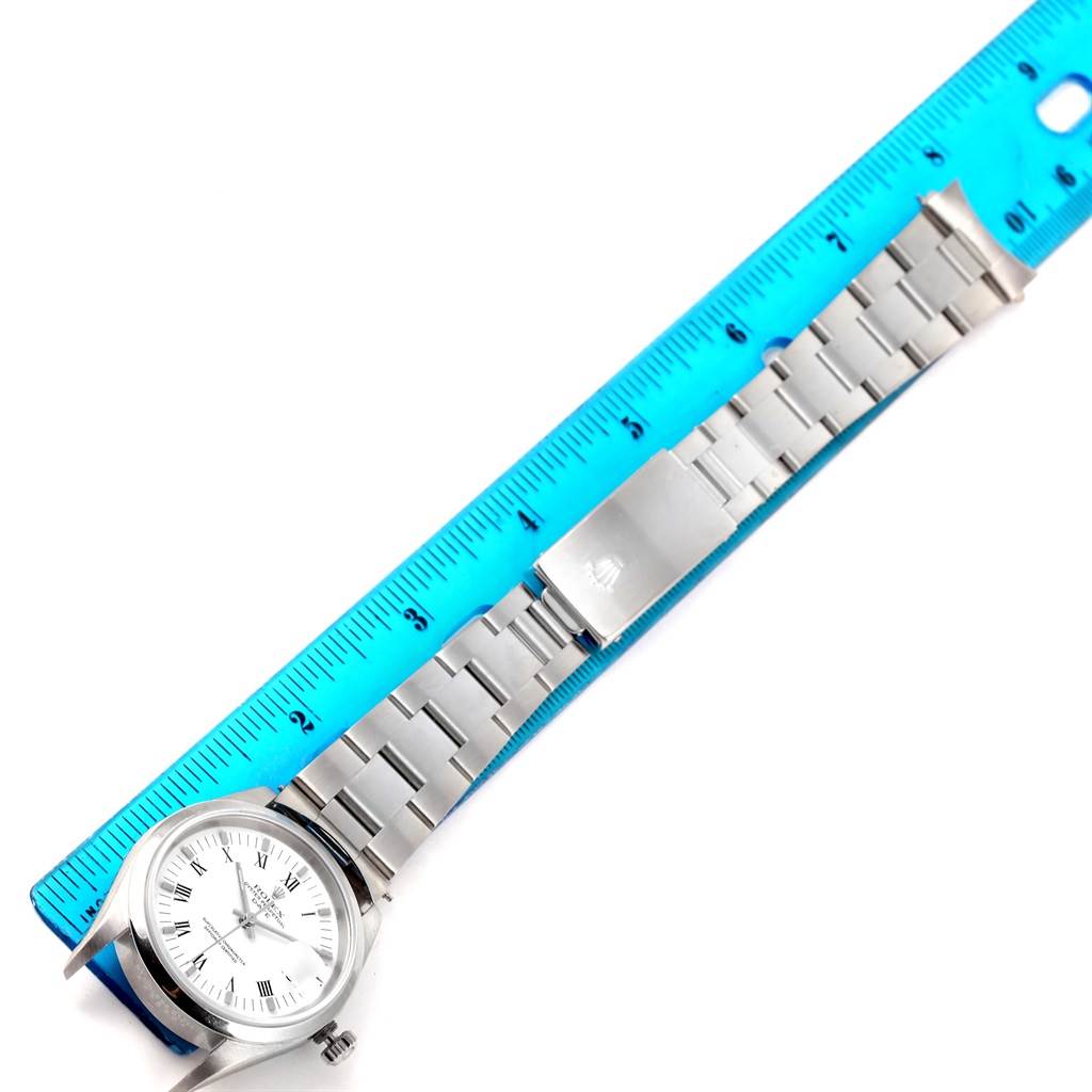 The Rolex Date 15200 Men's Stainless Steel White Dial 15200 Men's Stainless Steel White Dial model watch is shown from a top-down angle, displaying the face, crown, and bracelet aligned with a blue ruler.