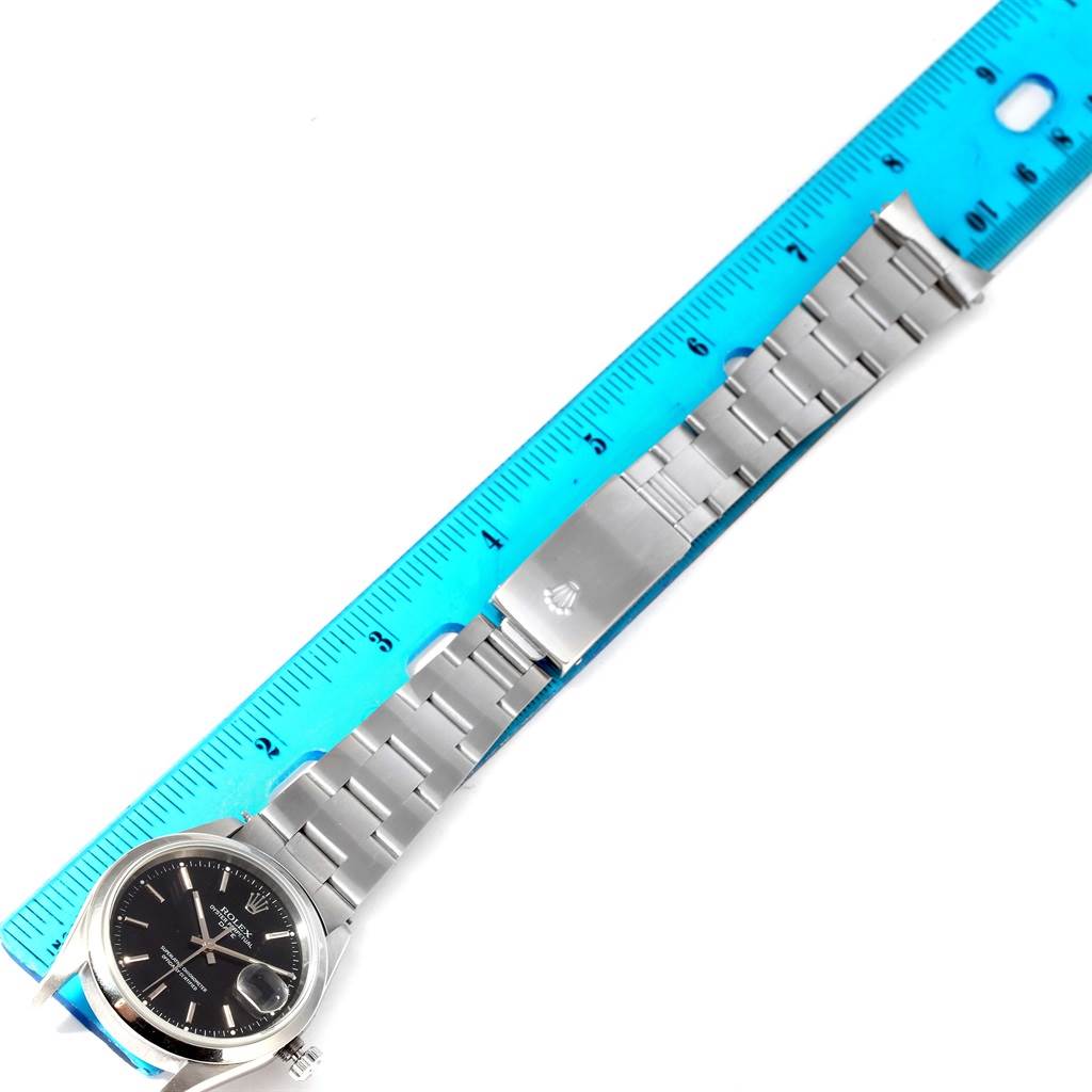 This image shows a Rolex Date 15200 Men's Stainless Steel Black Dial 15200 Men's Stainless Steel Black Dial model watch laid flat with a blue ruler aligned beside it.