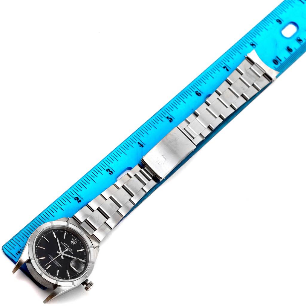 The Rolex Date 15210 Men's Stainless Steel Black Dial 15210 Men's Stainless Steel Black Dial model watch is displayed horizontally alongside a ruler, showing the bracelet, clasp, and face.