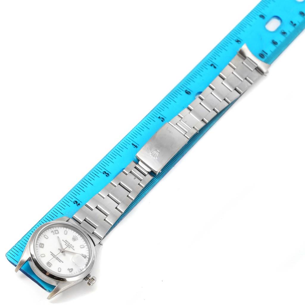 The Rolex Date 15200 Men's Stainless Steel White Dial 15200 Men's Stainless Steel White Dial model watch is shown laid flat with a blue ruler for measurement alongside its face and metal bracelet.