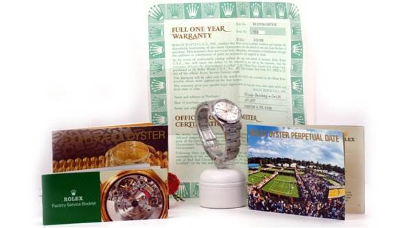 The Rolex Date 15200 Men's Stainless Steel Silver Dial 15200 Men's Stainless Steel Silver Dial model watch is shown standing upright surrounded by warranty, service booklet, and promotional cards.