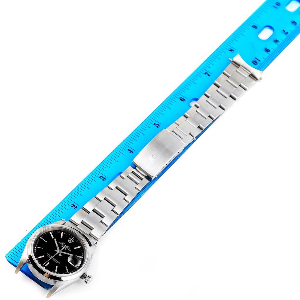 The Rolex Date 15200 Men
s Stainless Steel Black Dial 15200 Men
s Stainless Steel Black Dial watch is shown lying flat with its metal bracelet and buckle visible, measured against a blue ruler.