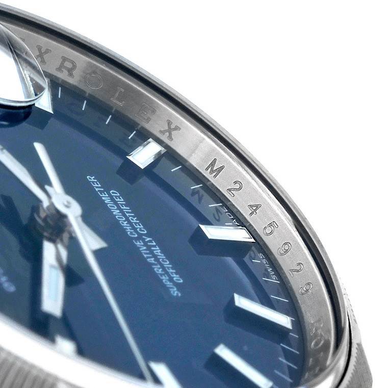 This close-up image shows the side of the Rolex Date 115210 Men's Stainless Steel Blue Dial 115210 Men's Stainless Steel Blue Dial watch bezel and part of its blue dial and hands.