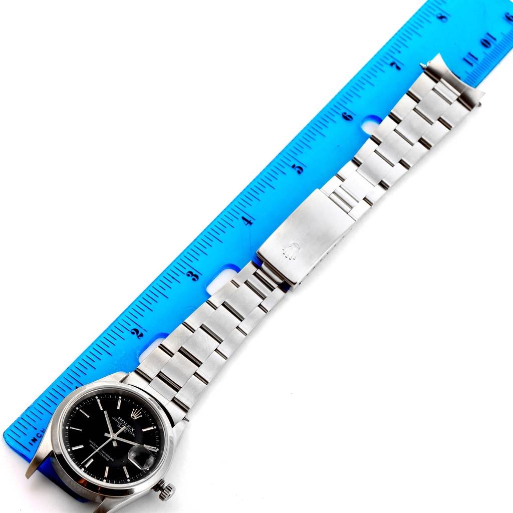 The image shows a Rolex Date 15200 Men
s Stainless Steel Black Dial 15200 Men
s Stainless Steel Black Dial watch lying flat next to a blue ruler, showcasing the watch face, bracelet, and clasp.