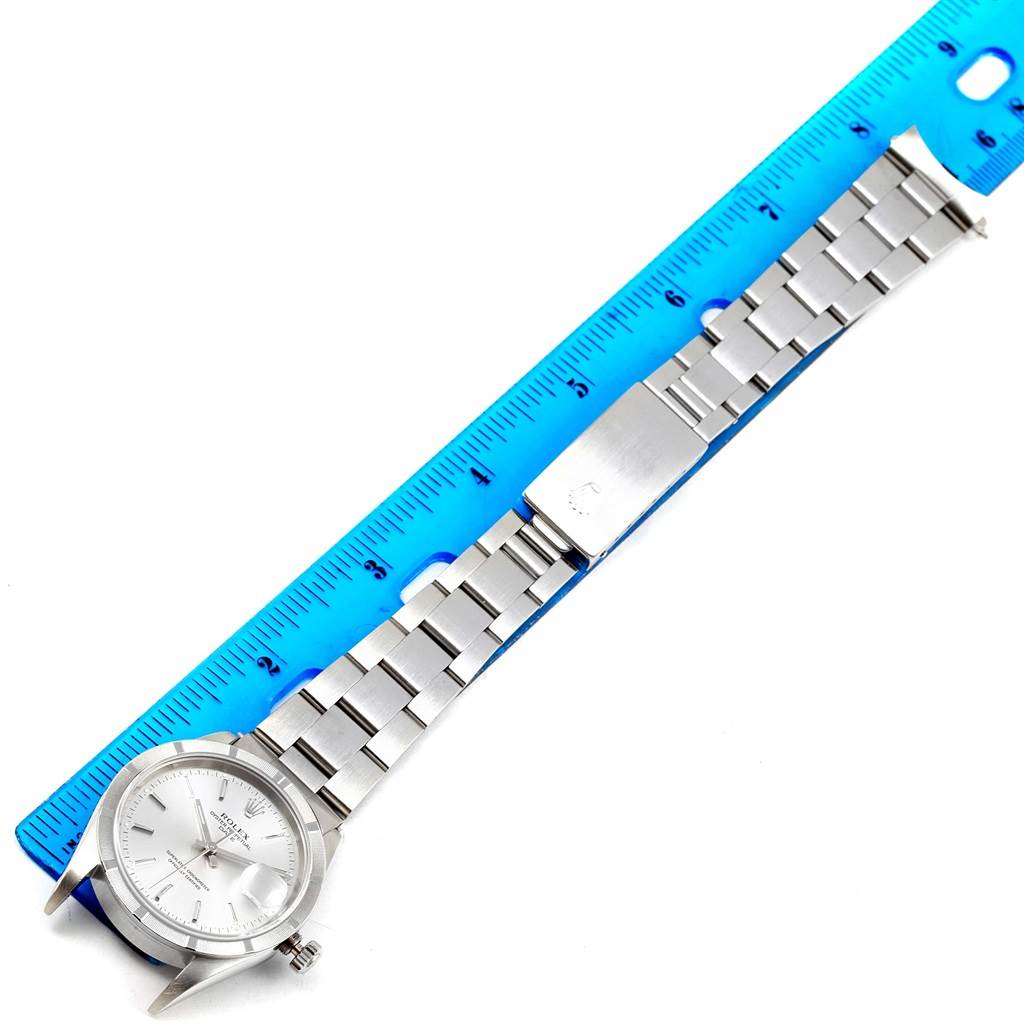 The image shows a Rolex Date 15210 Men's Stainless Steel Silver Dial 15210 Men's Stainless Steel Silver Dial model watch, including the face, case, bracelet, and clasp, with a blue ruler measuring the band length.