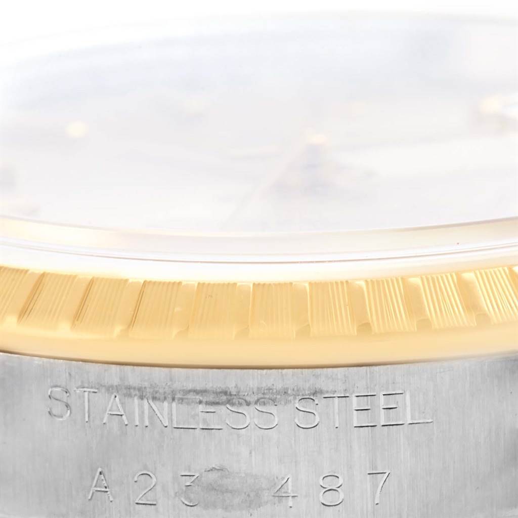 This close-up image of the Rolex Date 15223 Men's Steel and Gold (two tone) Silver Dial 15223 Men's Steel and Gold (two tone) Silver Dial model shows the edge of the case, the fluted bezel, and part of the watch's serial number.