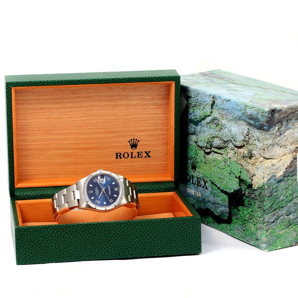 The Rolex Date 15210 Men's Stainless Steel Blue Dial 15210 Men's Stainless Steel Blue Dial model watch is shown from a front angle, inside its green and wooden display box, with the box cover beside it.