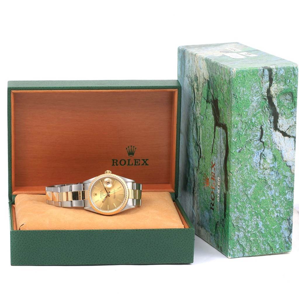 The image shows a Rolex Date 15223 Men's Steel and Gold (two tone) Champagne Dial 15223 Men's Steel and Gold (two tone) Champagne Dial model watch placed in its open rectangular box with the brand logo and green outer packaging beside it.
