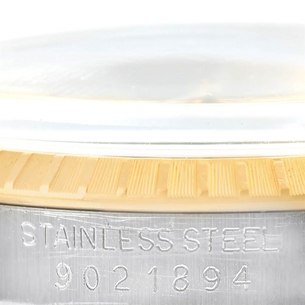 This close-up shows the case side and bezel of a Rolex Date 15053 Men's Steel and Gold (two tone) Champagne Dial 15053 Men's Steel and Gold (two tone) Champagne Dial model watch, engraved with "STAINLESS STEEL" and a serial number.