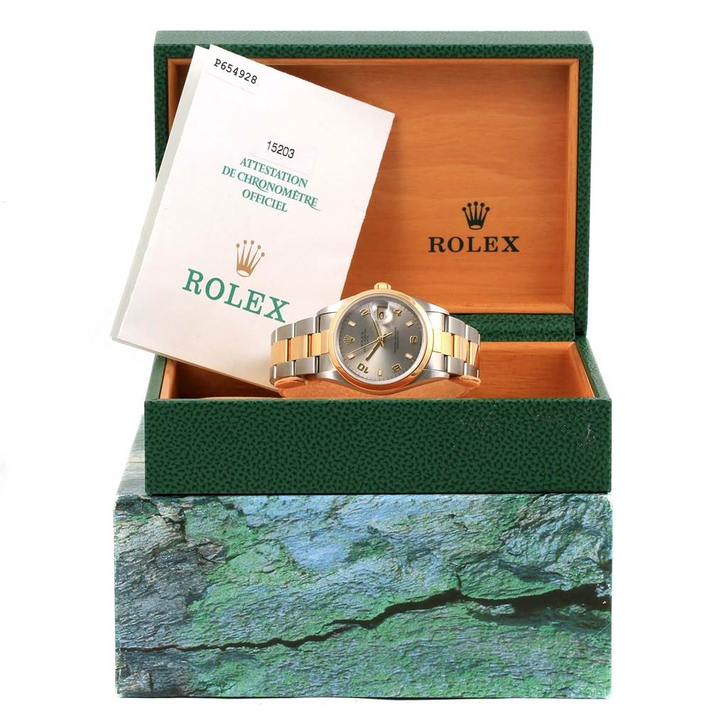 The image shows a Rolex Date 15203 Men's Steel and Gold (two tone) Grey Dial 15203 Men's Steel and Gold (two tone) Grey Dial model wristwatch in its open green box with a certificate booklet leaning against the box lid.