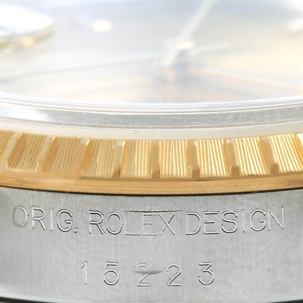 This image shows a close-up of the Rolex Date 15223 Men's Steel and Gold (two tone) Champagne Dial 15223 Men's Steel and Gold (two tone) Champagne Dial model's bezel and case, highlighting the "ORIG. ROLEX DESIGN" engraving with the model number 15223.