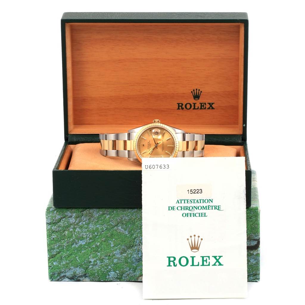 The Rolex Date 15223 Men's Steel and Gold (two tone) Champagne Dial 15223 Men's Steel and Gold (two tone) Champagne Dial watch is shown in its box, with the certificate partially covering the watch.