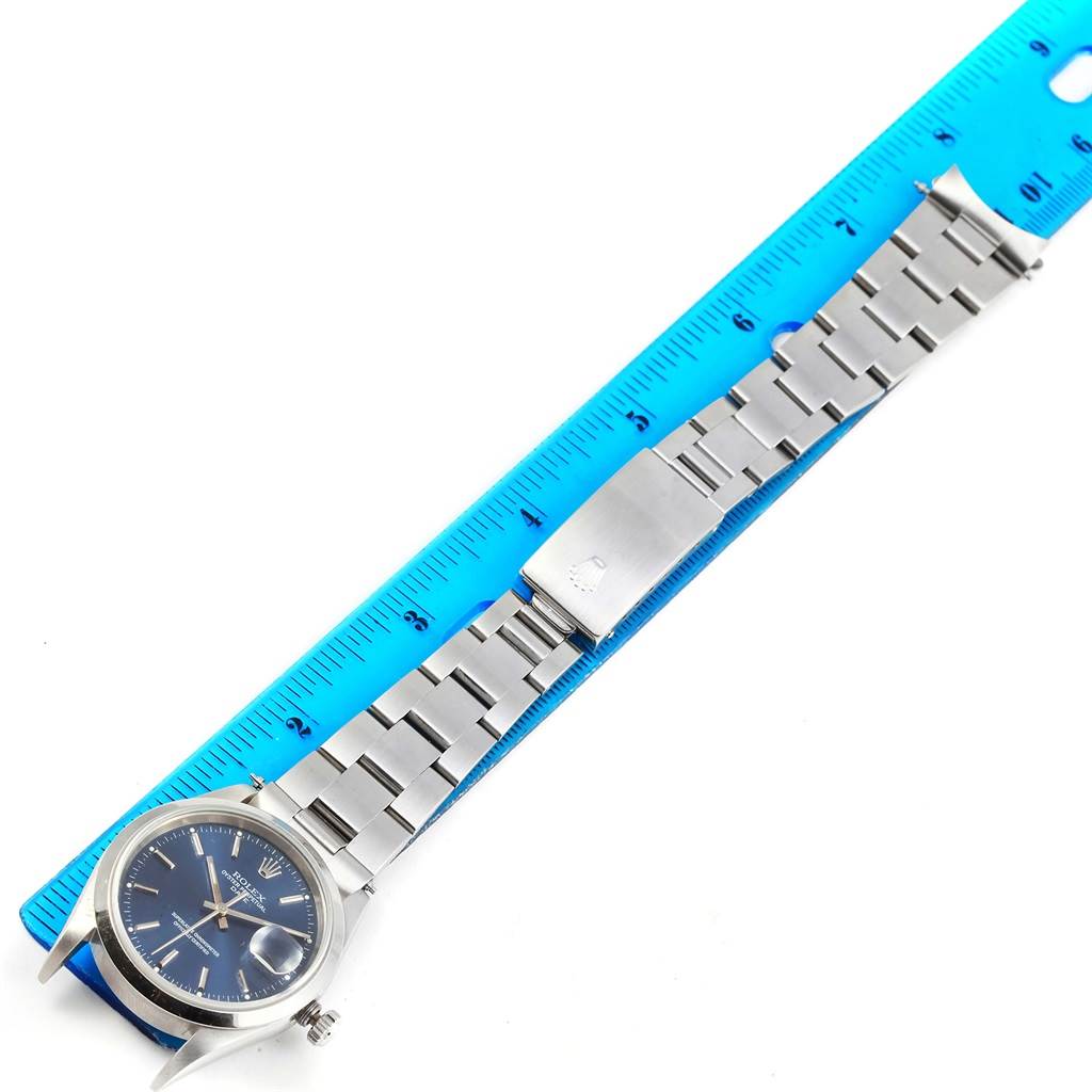 The Rolex Date 15200 Men's Stainless Steel Blue Dial 15200 Men's Stainless Steel Blue Dial model watch is shown fully extended next to a blue ruler, detailing the face and metal bracelet.