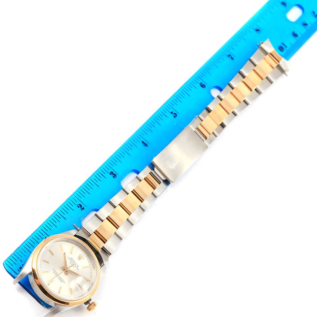 The Rolex Date 15203 Men's Steel and Gold (two tone) Silver Dial 15203 Men's Steel and Gold (two tone) Silver Dial watch is shown from a top-down angle, featuring the face, bracelet, and clasp, with a ruler next to it for scale.