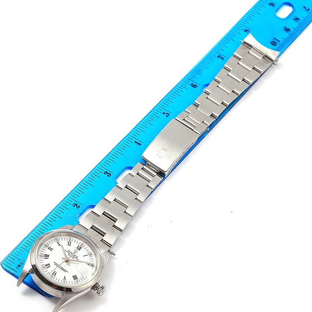 This image shows a Rolex Date 15200 Men's Stainless Steel White Dial 15200 Men's Stainless Steel White Dial model watch lying flat next to a blue ruler, focusing on its face and metal bracelet.