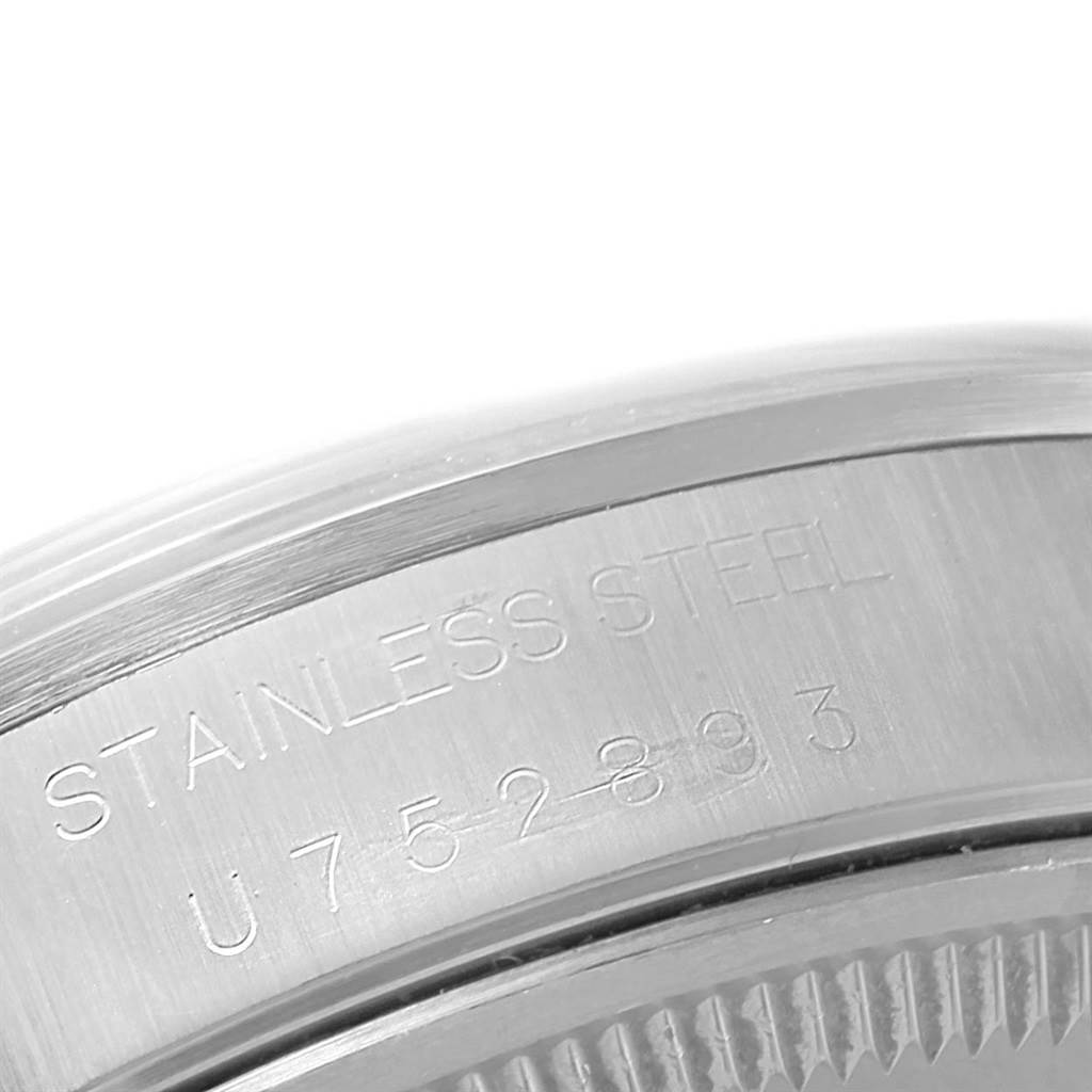 The image shows the engraved side of a Rolex Date 15200 Men's Stainless Steel White Dial 15200 Men's Stainless Steel White Dial model watch, specifically the serial number and "STAINLESS STEEL" marking.