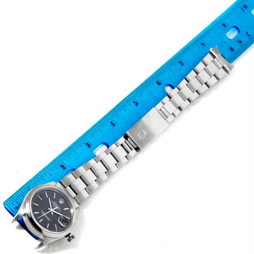 The Rolex Date 15200 Men's Stainless Steel Black Dial 15200 Men's Stainless Steel Black Dial model watch is shown flat, highlighting its face, bracelet, and clasp next to a blue ruler.