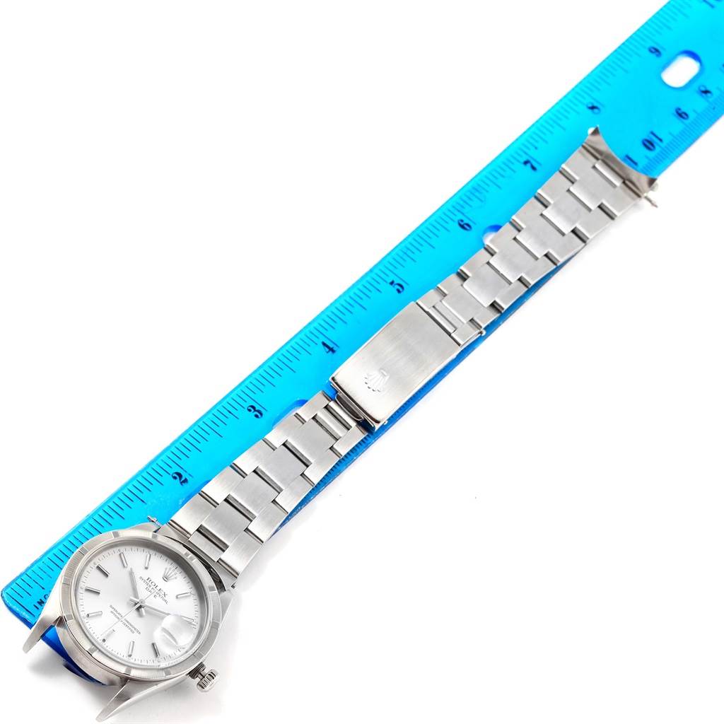 The image shows a Rolex Date 15210 Men's Stainless Steel Silver Dial 15210 Men's Stainless Steel Silver Dial model watch flat with its bracelet extended next to a blue ruler for scale.