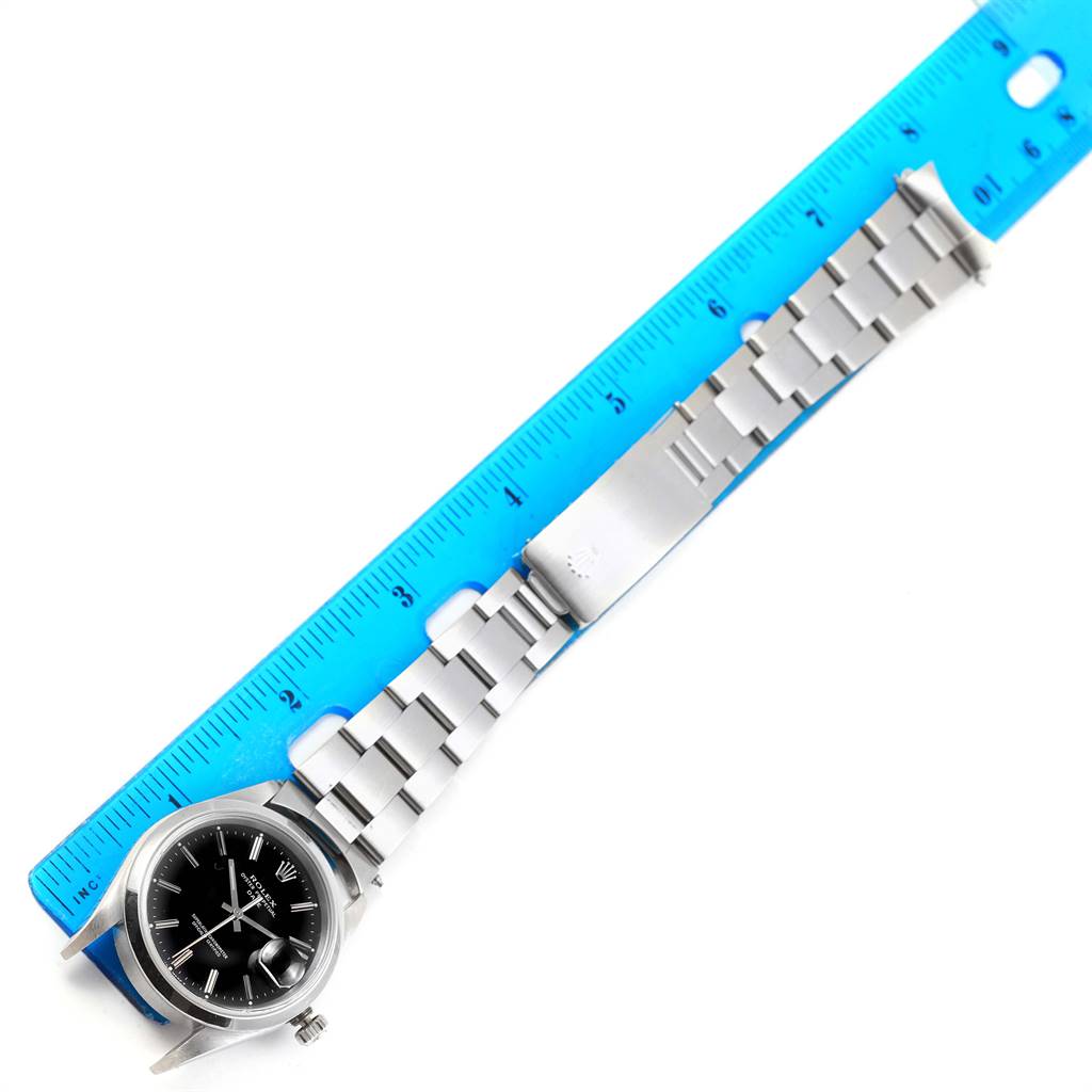 The Rolex Date 15200 Men's Stainless Steel Black Dial 15200 Men's Stainless Steel Black Dial model watch is shown fully extended beside a blue ruler, displaying its face and bracelet.