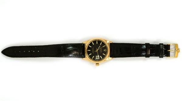 The image shows a top-down view of a Rolex Date 1503 Men's Yellow Gold Black Dial 1503 Men's Yellow Gold Black Dial model watch, featuring a black leather strap and a gold case with a black dial.