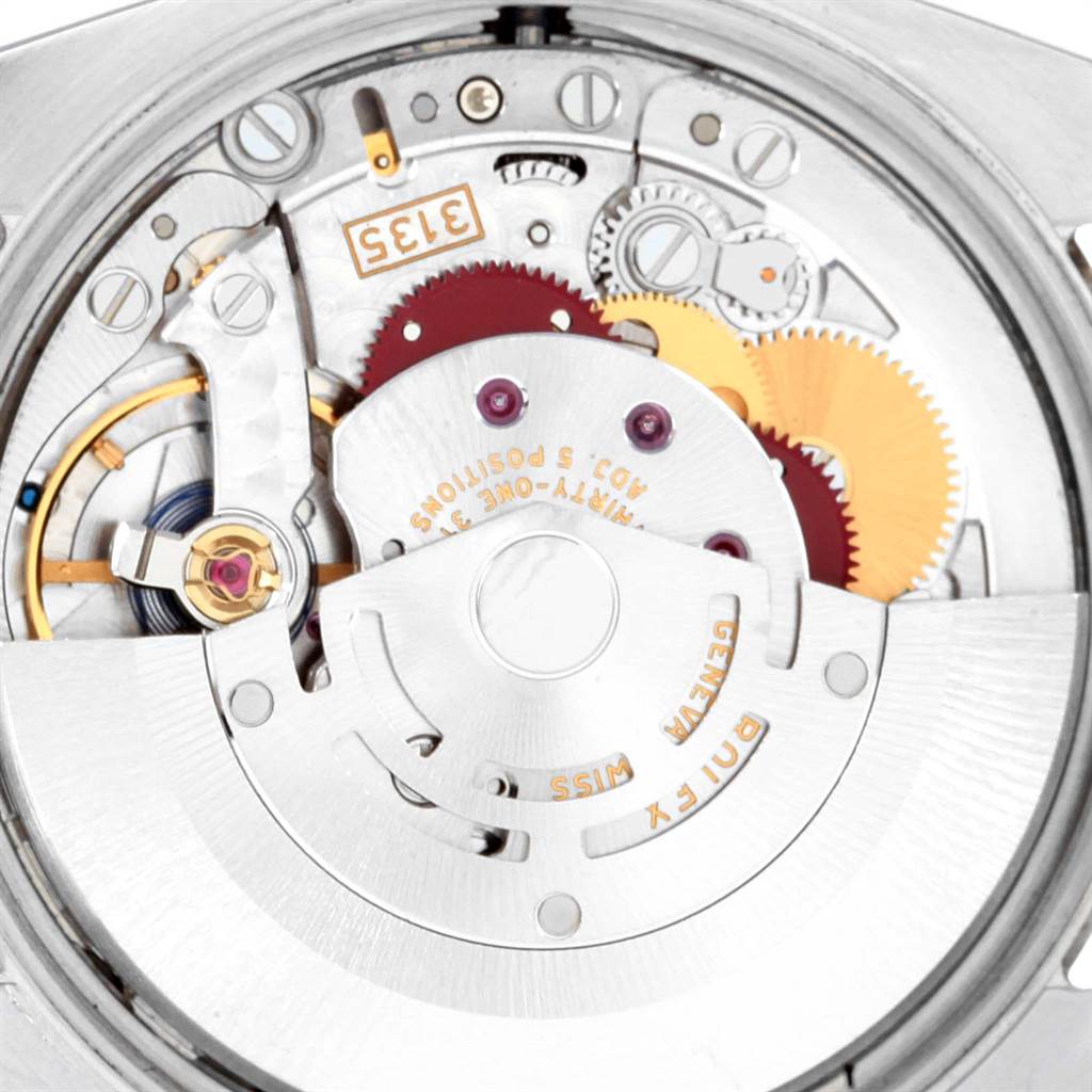 The image shows a close-up view of the movement mechanism inside a Rolex Date 115200 Men's Stainless Steel Black Dial 115200 Men's Stainless Steel Black Dial model watch, highlighting gears and internal components.