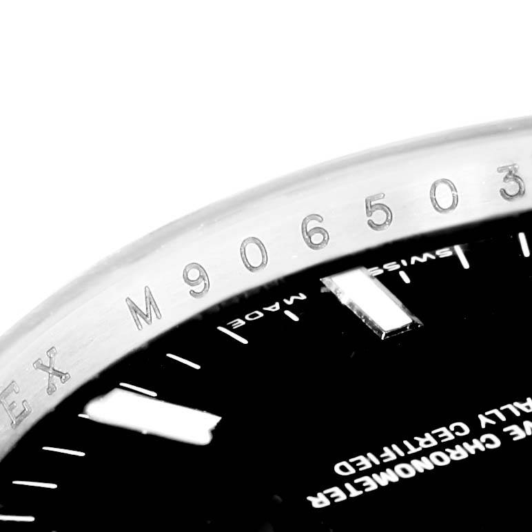 The image shows a close-up of the bezel, serial number, and part of the dial of the Rolex Date 115200 Men's Stainless Steel Black Dial 115200 Men's Stainless Steel Black Dial model.