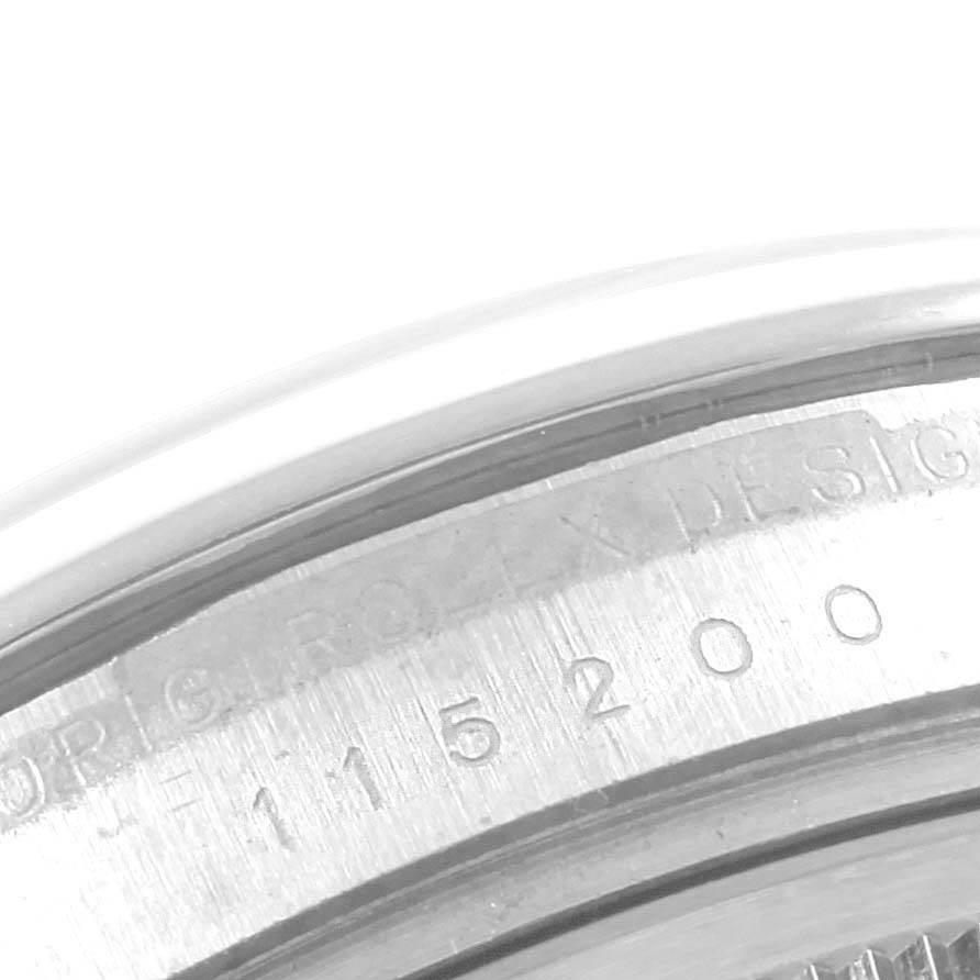 The image shows a close-up of the side engraving on a Rolex Date 115200 Men's Stainless Steel Black Dial 115200 Men's Stainless Steel Black Dial model watch, displaying part of its serial number and text.