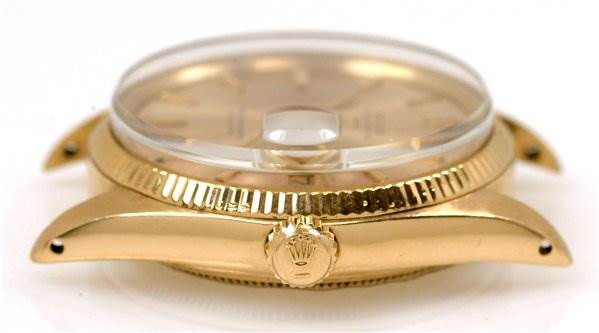 This is a side angle view of a Rolex Date 1503 Men's Yellow Gold Champagne Dial 1503 Men's Yellow Gold Champagne Dial model watch, showcasing its crown, case, and partially the crystal.