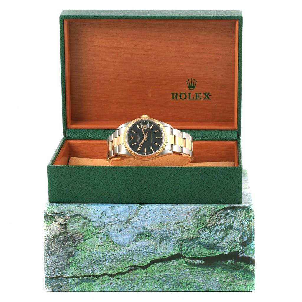 The Rolex Date 15223 Men's Steel and Gold (two tone) Black Dial 15223 Men's Steel and Gold (two tone) Black Dial model watch is shown in its green and wooden box with the watch facing forward to display the dial and bracelet.