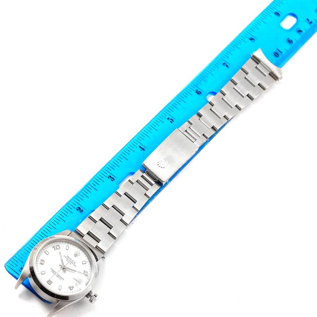 The image shows a top view of the Rolex Date 15200 Men's Stainless Steel White Dial 15200 Men's Stainless Steel White Dial model watch with its stainless steel band against a blue ruler.