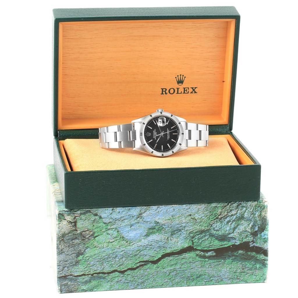 The Rolex Date 15210 Men's Stainless Steel Black Dial 15210 Men's Stainless Steel Black Dial model watch with a black dial is shown at a front angle in its green and yellow box.