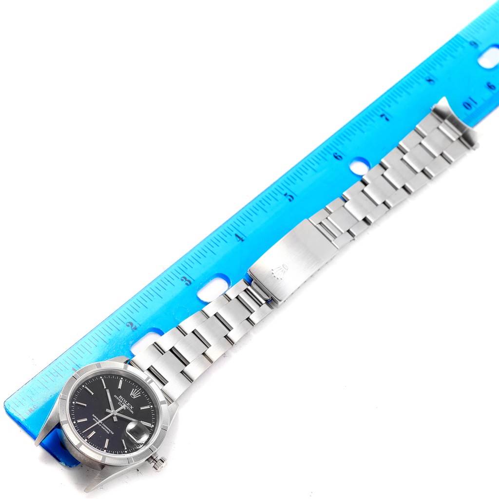 The image shows a top-down view of a Rolex Date 15210 Men's Stainless Steel Black Dial 15210 Men's Stainless Steel Black Dial model watch and its metal bracelet alongside a ruler.