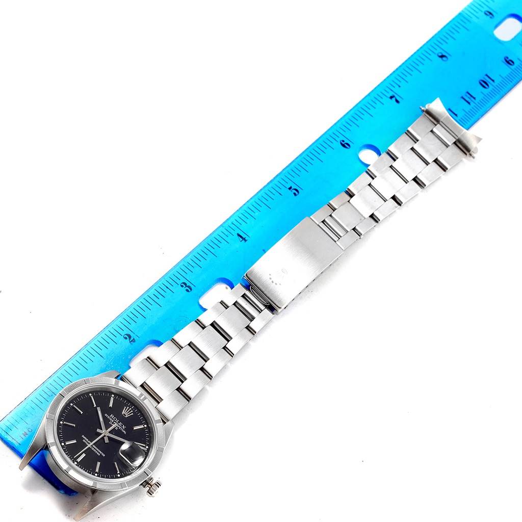 The image shows a Rolex Date 15210 Men's Stainless Steel Black Dial 15210 Men's Stainless Steel Black Dial model watch, displaying its face, bracelet, and clasp, with a ruler for size reference.