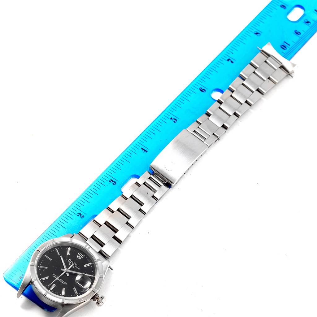 The image shows a full-length view of a Rolex Date 15210 Men's Stainless Steel Black Dial 15210 Men's Stainless Steel Black Dial model watch, including its face and metal bracelet, placed next to a blue ruler.